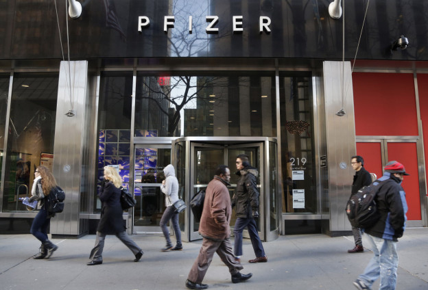 People walk past Pfizer's world headquarters Monday Nov. 23 2015 in New York. Pfizer and Allergan will join in a $160 billion deal to create the world's largest drugmaker