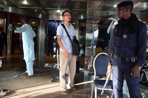 UNDER GUARD A guest leaves the Radisson Blu hotel in Bamako on November 21 after coming to retrieve his belongings a day after a deadly attack. Investigators in Mali are hunting at least three people suspected of links to the jihadist siege at the luxury