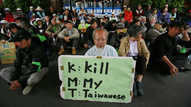 Protesters against Taiwan's trade pact with China stage a sit-in outside parliament with a sign denouncing the ruling Kuomintang in 2014