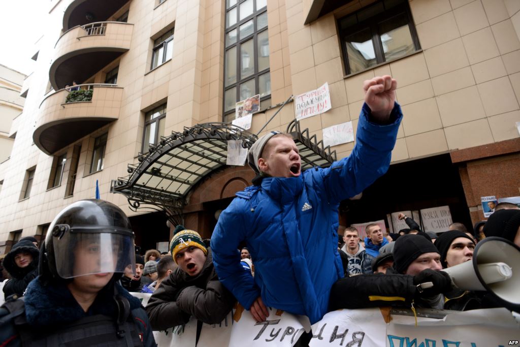 Protesters hold placards and shout slogans in front of the Turkish Embassy in Moscow on November 25