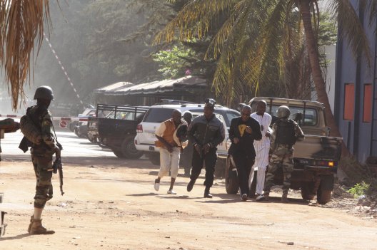 People run to flee from the Radisson Blu Hotel in Bamako Mali Friday Nov. 20 2015. The company that runs the Radisson Blu Hotel in Mali's capital says assailants have takenhostages in a brazen assault involving grenades