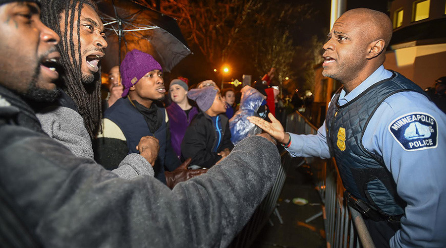 A police officer talks with demonstrators in front of a north Minneapolis police precinct during a protest in response of Sunday's shooting death of Jamar Clark by police officers in Minneapolis Minnesota