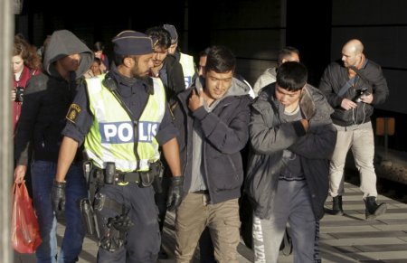 A group of migrants coming off an incoming train are seen next to a police officer on the platform at the Swedish end of the bridge between Sweden and Denmark in Hyllie district Malmo