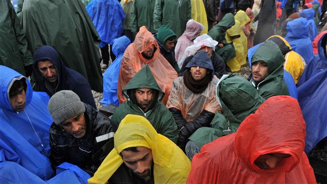 Rejected refugees sit on railway tracks as they wait under the rain to cross the Greek Macedonian border near Idomeni