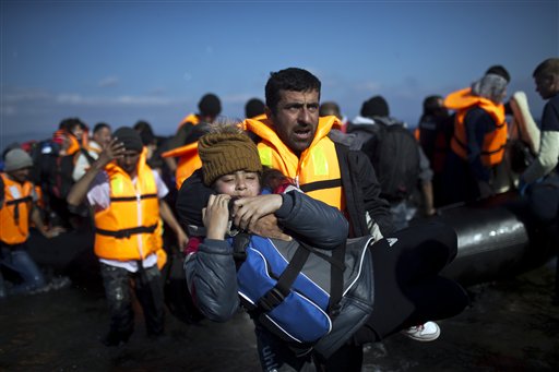 A man carries a child after travelling by rubber boat to a beach on the northern shore of Lesbos Greece Saturday Nov. 7 2015. Well over half a million people have reached the Greek islands so far this year a record number of arrivals and the journey