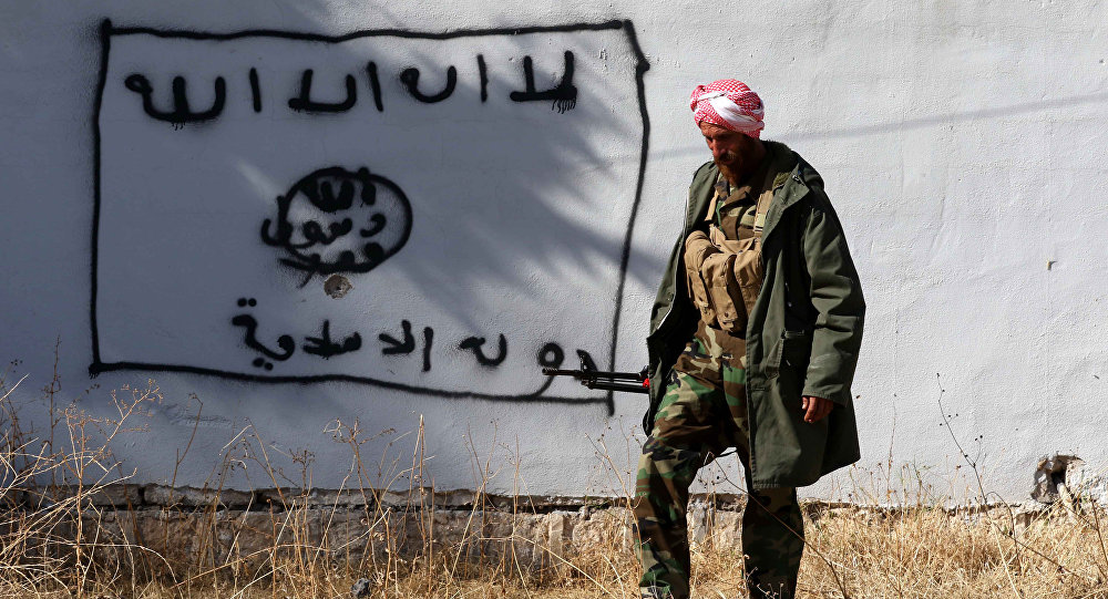 A Kurdish fighter walks by a wall bearing a drawing of the flag of the Islamic State group in the northern Iraqi town of Sinjar in the Nineveh Province