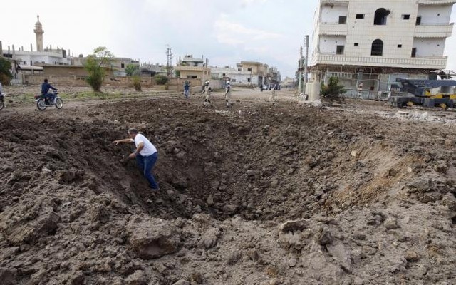 A man walks out of a crater caused by what activists said was a barrel bomb dropped by forces loyal to Syria's President Bashar Al Assad in the town of Dael north of Deraa