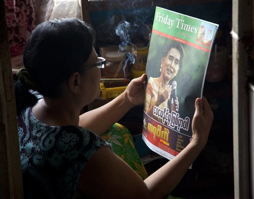 A woman reads a newspaper with Myanmar opposition leader Aung San Suu Kyi on the cover at her residence Thursday Nov 12 2015 on outskirts of Yangon Myanmar. Nobel laureate Aung San Suu Kyi's opposition party was on the verge of a formal victory