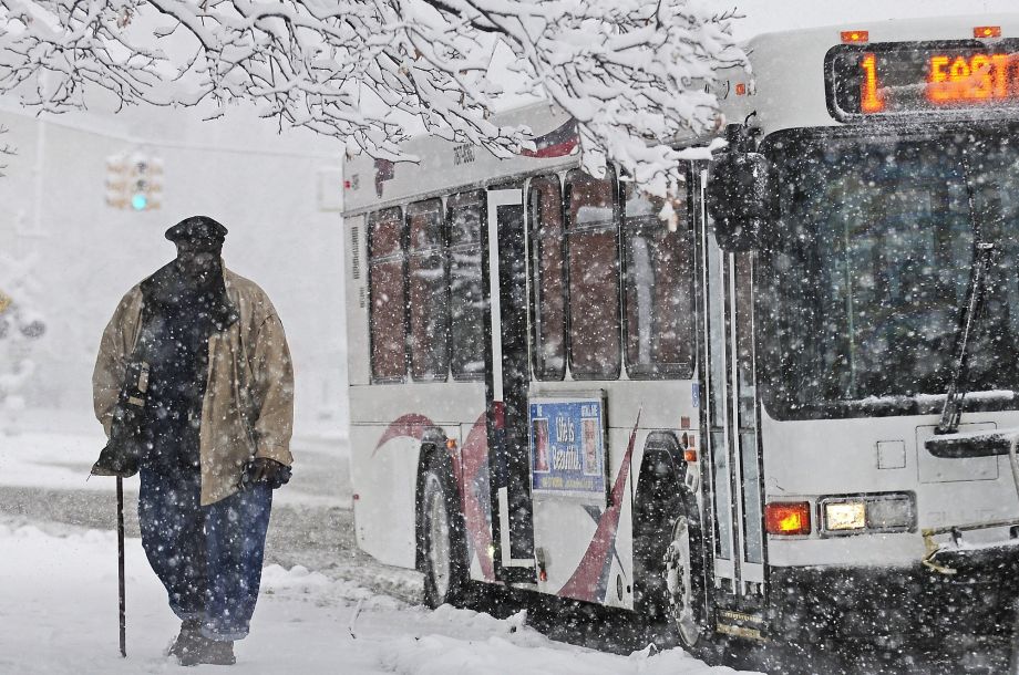 A man exits a bus on East Michigan Avenue as snow falls in Jackson Mich. Saturday Nov. 21 2015. The first significant snowstorm of the season blanketed some parts of the Midwest with more than a foot of snow and more was on the way Saturday creating