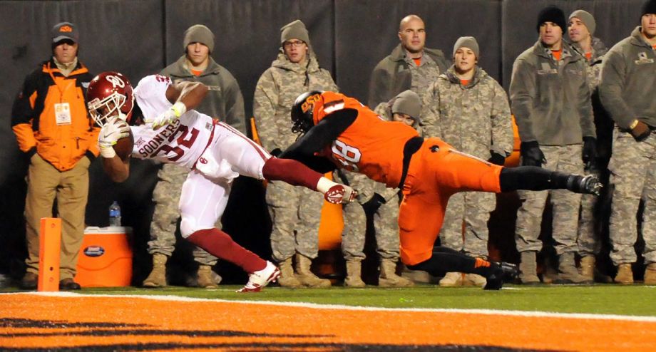 Oklahoma running back Samaje Perine crosses the goal line while being chased by Oklahoma State defensive end Emmanuel Ogbah during the first half of an NCAA college football game in Stillwater Okla. Saturday Nov. 28 2015