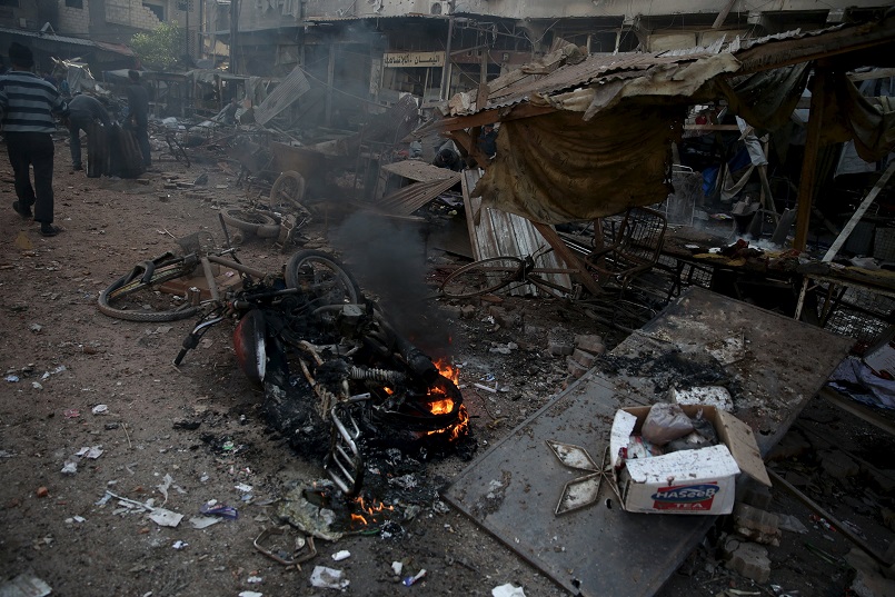 People inspect a site hit by missiles fired by Syrian government forces on a busy marketplace in the Douma neighborhood of Damascus Syria