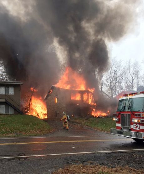 A firefighter walks up a driveway as an apartment building burns in Akron Ohio Tuesday Nov. 10 2015 where authorities say a small business jet crashed. The plane burst into flames and disintegrated after impact. It was unclear how many people were