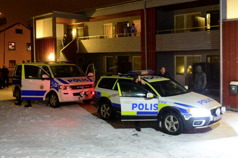 Swedish police stand by police cars outside a house used as a temporary shelter for asylum seekers in Boliden in northeastern Sweden