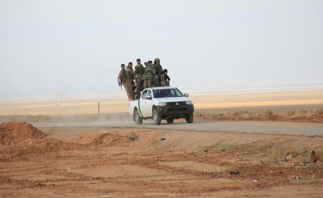 Syrian pro-government forces ride on a pickup truck on the only road into the government-held side of Aleppo