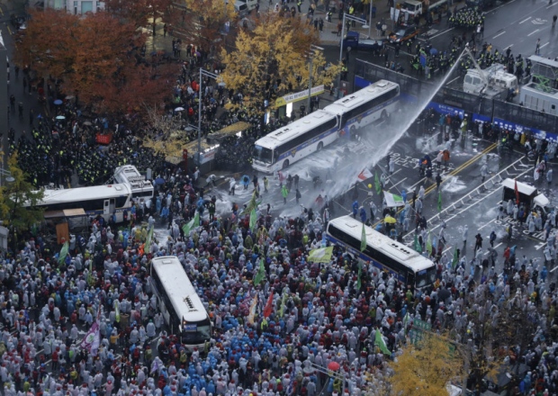 South Korean riot police officers spray a water cannon as police officers try to break up protesters who try to march to the Presidential House