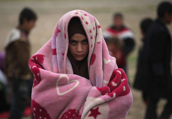 A girl bundles against the cold while fleeing to Sinjar Iraq from a village held by ISIS