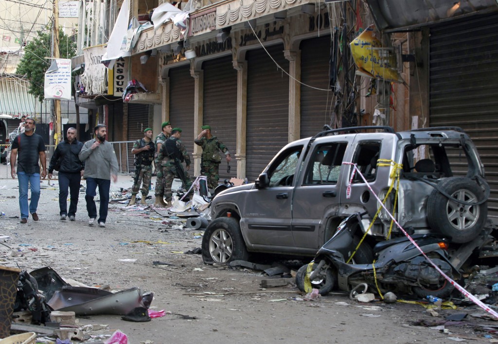 Lebanese army soldiers and Hezbollah members gather at the scene of Thursday's twin suicide bombings in Burj al-Barajneh southern Beirut Lebanon Friday Nov. 13 2015. Schools and universities across Lebanon were shuttered Friday as the country