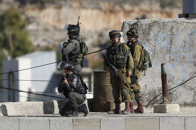 Israeli security troops take positions at the scene of a stabbing attempt in the Beit Einun junction east of the West Bank city of Hebron Sunday Nov 1 2015. The Israeli military said soldiers shot a Palestinian who had tried to stab them on Sunday