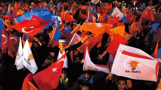 People wave flags outside the AK Party headquarters in Istanbul yesterday following the outcome of a general election which swept the party back to a parliamentary majority