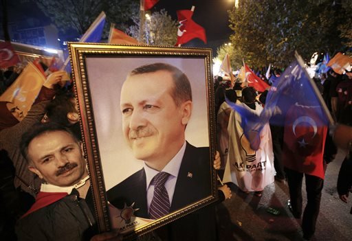 A supporter of the Justice and Development Party  holds a portrait of Turkey's President Recep Tayyip Erdogan as people celebrate outside the AKP headquarters in Istanbul Turkey late Sunday Nov. 1 2015. Turkey's ruling party secured a stunning