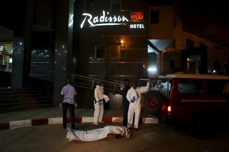 Malian officials prepare to lift a corpse into an emergency vehicle outside the Radisson hotel in Bamako Mali