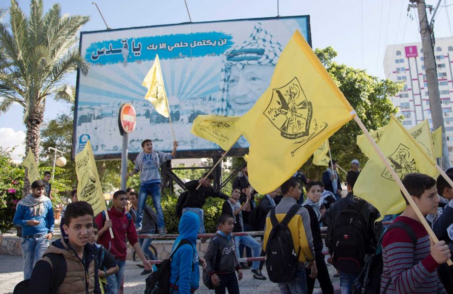 Palestinian students wave yellow Fatah flags in front of a billboard of late Palestinian President Yasser Arafat during a celebration marking the 11th anniversary of his death in Gaza City Wednesday Nov. 11 2015. Arabic reads' my dream not complete