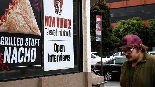 A pedestrian walks by a 'now hiring&#039 sign at a KFC restaurant in San Francisco