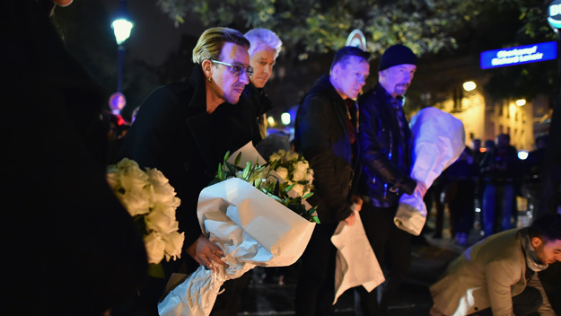 Bono and band members from the band U2 place flowers on the pavement near the scene of yesterday's Bataclan Theatre terrorist attack