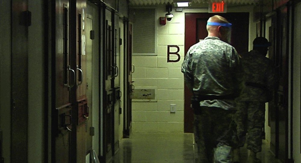 Soldiers walk past detainees cells during early morning prayer at Guantanamo Bay Naval Base Camp 5 in Cuba