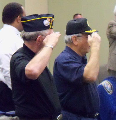 Veterans salute as the American flag is posted