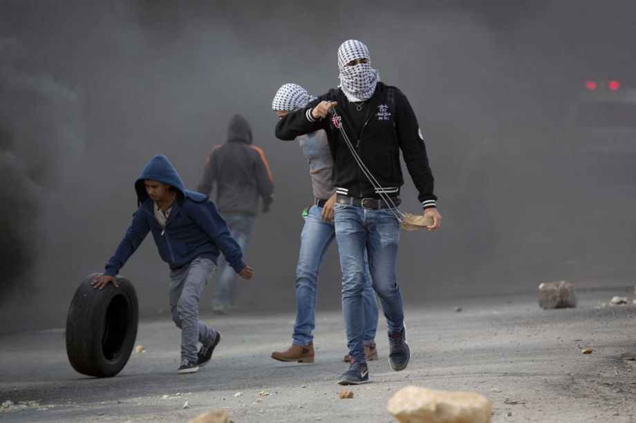 Palestinian protesters prepare to throw stones towards Israeli troops during clashes outside Ofer military prison near the West Bank city of Ramallah Tuesday Nov. 3 2015