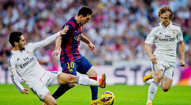 MADRID SPAIN- OCTOBER 25 Isco of Real Madrid CF tackles Lionel Messi of Barcelona during the La Liga match between Real Madrid CF and FC Barcelona at Estadio Santiago Bernabeu