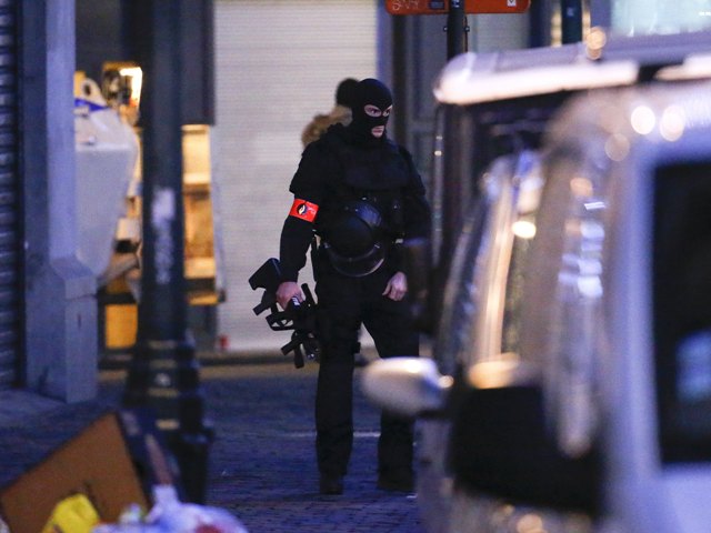 A Belgian special forces police officer patrols a street during a police raid in central Brussels Belgium