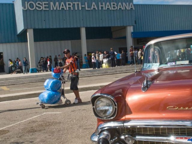 A Cuban American pases by a vintage Chevrolet as he arrives from Miami at Havana's international airport