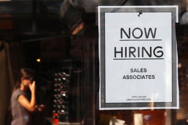 A'Now Hiring sign hangs on the door of an Urban Outfitters store at Quincy Market in Boston