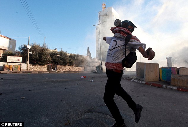 A Palestinian protester hurls stones towards Israeli troops during clashes in the West Bank city of Bethlehem today