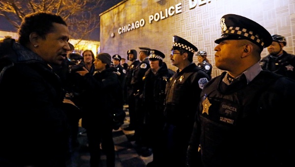 A demonstrator faces a line of police in front of the Chicago Police Department during protests in Chicago