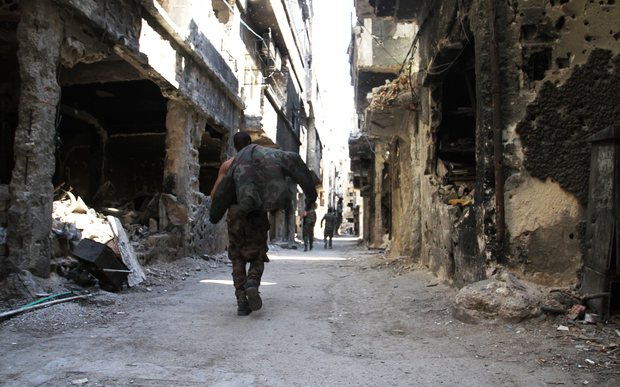 Men walk past destroyed buildings in the Yarmuk Palestinian refugee camp in the Syrian capital Damascus