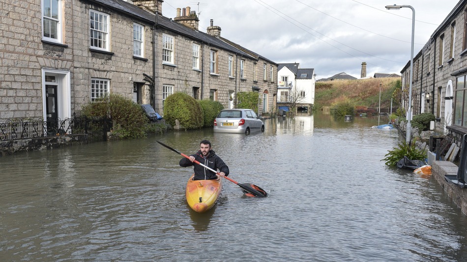 A man uses a canoe to access his home on Gandy Street in Kendal UK on Dec. 6 2015. More rain is expected for northwest England