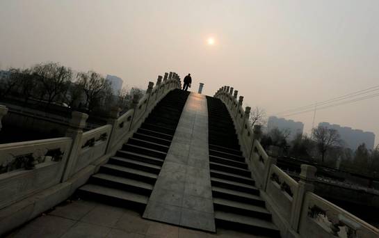 A man walks on a bridge on a hazy day in Beijing China