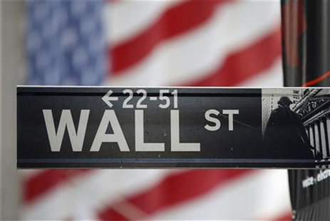 A sign for Wall Street is seen with a giant American flag in the background across from the New York Stock Exchange