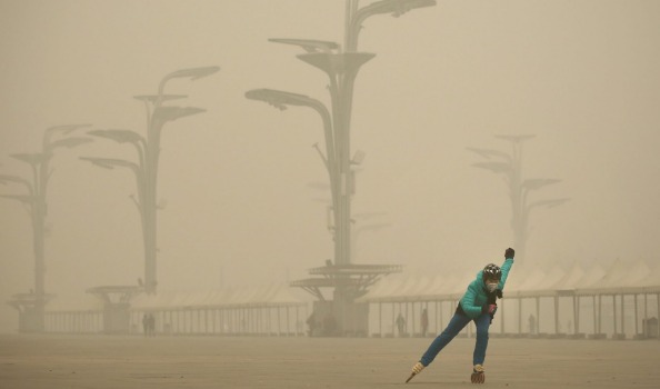 A woman wearing a mask practices roller blading at Olympic Park during heavy smog in Beijing China