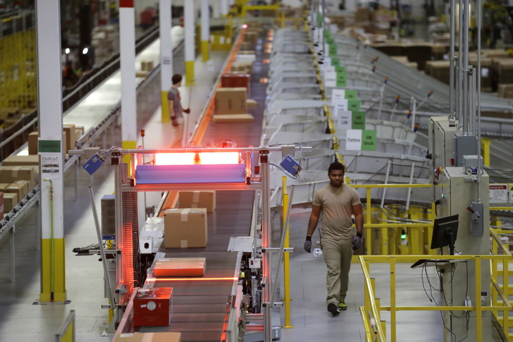 A worker walks near a high-speed scanning conveyor belt Nov. 30 at Amazon’s fulfillment center in DuPont