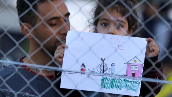 A young migrant girl holds up a drawing in a makeshift camp on the Macedonian Greek border near Gevgelija Macedonia Nov. 30 2015