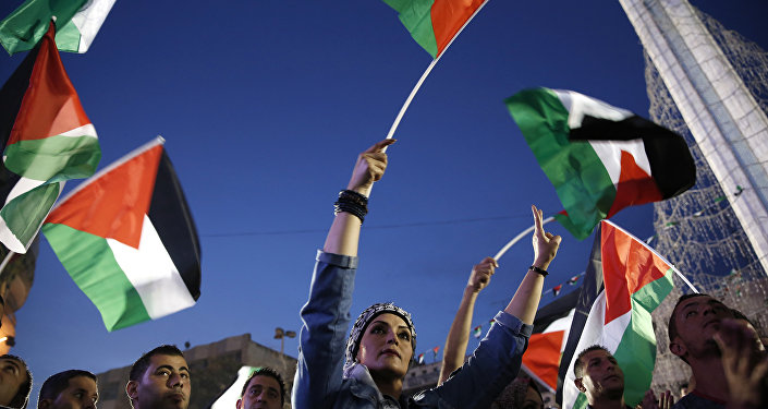 Palestinians wave their national flags as they watch a live-screening of president Mahmud Abbas speech followed by the raising of the Palestinian flag at the United Nations headquarters in New York