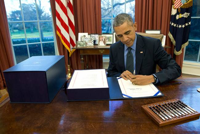 President Barack Obama signs the budget bill in the Oval Office of the White House Friday Dec. 18 2015 in Washington