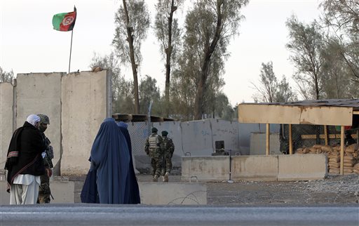 Civilians wait as Afghan security forces guard at the main gate of Kandahar civilian airport during a clash between Taliban fighters and Afghan forces in Kandahar Afghanistan Wednesday Dec. 9 2015. An Afghan official says the Taliban have launched