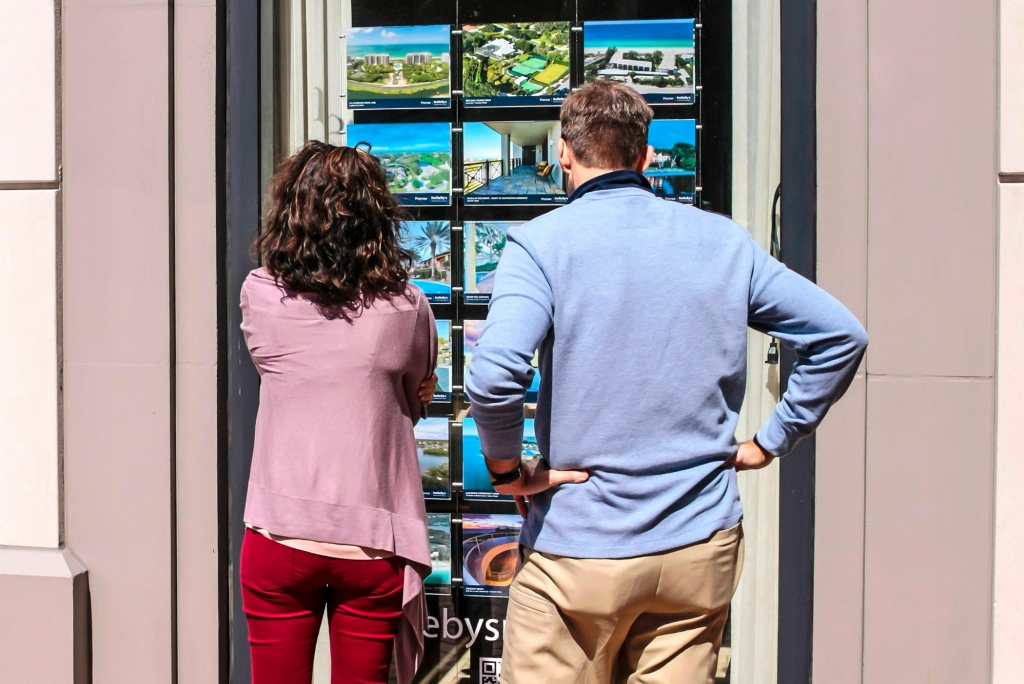 A couple looks at a window display of homes for sale outside a real estate brokers office in Sarasota Florida