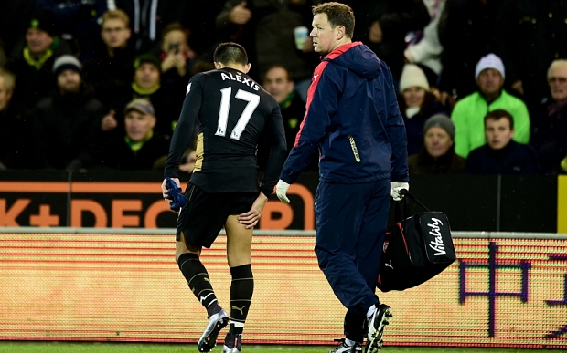 Alexis Sanchez clutches his leg as he exits the pitch at Carrow Road