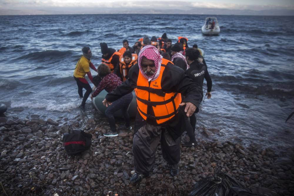 An Iraqi man disembarks from a dinghy on a beach after his trip with other refugees and migrants from the Turkish coast to the northeastern Greek island of Lesbos on Friday Dec. 18 2015. European Union leaders on Thursday set a six-month deadline for